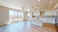Located at 2100 Fourth Avenue in San Diego, this thoughtfully designed 2-bedroom, 2-bathroom residence offers a bright, open-concept layout with contemporary finishes throughout. The combined kitchen and living area serves as the heart of the home, featuring light-toned hardwood-style flooring, a ceiling fan, and expansive windows that flood the space with natural light while framing views of the San Diego skyline. A private balcony extends the living area outdoors. The kitchen is well-appointed with crisp white shaker cabinetry, stone tile backsplash, light quartz countertops, a central island, stainless steel appliances including a gas range, microwave, refrigerator, and dishwasher. A hallway connects the main living area to the two generously sized bedrooms, both carpeted for comfort. The spacious primary bedroom offers ample room and is complemented by closet storage. The bathrooms are finished in neutral tones, with one featuring a frameless glass walk-in shower with floor-to-ceiling tile, built-in shelving niche, and backlit mirrors. Additional highlights include three closets, an in-unit laundry area, and a clean, neutral palette that creates a bright and welcoming ambiance throughout.