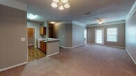 Located in Greenville, SC, this single-floor residence offers a well-organized and functional layout designed for comfortable everyday living. The open-concept main living area is generously sized, featuring soft wall-to-wall carpeting, neutral taupe walls, and a textured ceiling. A ceiling fan keeps the living room comfortable, while a glass exterior door invites natural light and provides access to the outdoors. An elegant chandelier highlights the adjacent dining area, which flows seamlessly into the kitchen.

The kitchen is designed with practicality in mind, featuring warm honey-toned wood cabinetry, light countertops, and a peninsula with a breakfast bar overhang. It is equipped with a full suite of white appliances, including a refrigerator, electric range with overhead exhaust, and dishwasher. Hardwood-style flooring grounds the kitchen space.

The bedrooms are carpeted and bathed in natural light through windowed walls fitted with blinds. Ceiling fans add comfort, and at least one bedroom includes a walk-in closet with built-in rod storage. The bathrooms feature hardwood-style flooring, warm wood vanity cabinetry, and light countertops. One bathroom offers a tiled tub-shower combination, while the other presents a longer vanity with a large mirror and additional storage. Crown molding accents select areas, adding a refined touch throughout.