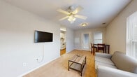 Located at 7 Traders Cir in Normal, IL, this one-bedroom, two-bathroom unit offers a practical and efficiently designed single-floor layout. The living room features warm carpeted flooring, a ceiling fan with light fixture, and a wall-mounted television. A window with blinds allows natural light to filter in, creating a bright and open feel. The space accommodates both a seating area and a dining set, making it functional for everyday living. The kitchen is outfitted with hardwood-style flooring, light wood cabinetry with warm-toned hardware, white appliances including a refrigerator, electric range, and dishwasher, along with a double-basin sink and under-cabinet ventilation. The bedroom is a cozy, carpeted room with a ceiling fan and a closet, providing a quiet retreat. Both bathrooms are well-appointed; one features dark tile flooring, a vanity with a large mirror, and a glass-enclosed shower. A dedicated utility room adds practical storage and laundry functionality to the unit. Overall, the space maintains a clean, neutral aesthetic with consistent finishes throughout, making it a straightforward and functional home.