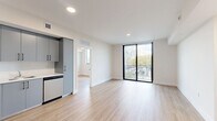 Located at 1559 Northwest 15th Street Road in Miami, FL, this modern 1-bedroom, 2-bathroom unit offers a thoughtfully designed layout with clean lines and contemporary finishes throughout. Light wood-look flooring flows seamlessly across the entire space, creating a bright, cohesive aesthetic.

The open-concept kitchen and living area serves as the heart of the unit. The kitchen features sleek gray cabinetry with black hardware, white quartz countertops, a subway tile backsplash, and a full suite of stainless steel appliances including a range, dishwasher, refrigerator, and microwave. The adjacent living area is bathed in natural light from large floor-to-ceiling sliding glass doors that open to a private balcony overlooking the Miami cityscape and lush tree canopy.

The bedroom is a comfortable, well-proportioned retreat with a large window framing outdoor views, a ceiling fan, and access to a dedicated walk-in closet equipped with wire shelving for organized storage. Both bathrooms are finished with large-format beige tile surrounding a full soaking tub and shower combination, paired with neutral tile flooring for a clean, modern look. The unit's bright white walls and recessed lighting throughout contribute to its fresh, move-in-ready appeal.