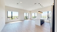 Located at 1300 40th St in Denver, CO, this thoughtfully designed 2-bedroom, 2-bathroom residence offers a clean, contemporary aesthetic throughout. The open-concept kitchen and living area serves as the heart of the home, anchored by large floor-to-ceiling windows and a private balcony access that floods the space with natural light and frames sweeping views of the Denver skyline and surrounding treetops. Light wood-tone flooring runs seamlessly through the main living areas, enhancing the airy, modern feel.

The chef-inspired kitchen features bold dark cabinetry contrasted against bright white quartz countertops, stainless steel appliances, and a central island topped with stylish globe pendant lights — ideal for both meal prep and casual dining. A clean white subway tile backsplash adds a polished finish.

The bedrooms are carpeted for warmth and comfort, each offering generous proportions and ample natural light. The primary bedroom includes a spacious walk-in closet with built-in shelving and hanging rods, as well as an en-suite bathroom showcasing a sleek dark vanity with gold hardware, white quartz counters, and a large mirror with modern globe lighting. Additional closets and a utility room provide practical storage throughout. The overall palette of crisp whites and deep charcoals creates a striking, cohesive modern aesthetic.