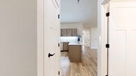This single-story, 2-bedroom, 2-bathroom home offers a thoughtfully designed layout with modern finishes throughout. Light hardwood flooring extends across the main living areas, complemented by soaring vaulted ceilings that lend an open, airy feel to the space. The open-concept kitchen and living room form the heart of the home, where the kitchen stands out with warm taupe shaker-style cabinetry, white quartz countertops with under-cabinet lighting, stainless steel appliances including a refrigerator, range, microwave, and dishwasher, and a central island ideal for dining or meal prep. The living area flows seamlessly from the kitchen, featuring recessed lighting and Craftsman-style interior doors with matte black hardware throughout. The generously sized primary bedroom includes plush carpeting, a ceiling fan, and sliding glass door access to the outdoors. The second bedroom also features carpet, a ceiling fan, and a window with natural views. Both bathrooms are finished with wood-toned vanities, white countertops, and stylish vanity lighting. A dedicated laundry room with upper cabinetry houses full-sized washer and dryer units. Two closets provide ample storage, completing this well-equipped, move-in-ready home.
