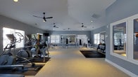 Located at 8439 Dorchester Rd in North Charleston, South Carolina, this fitness center offers a generously sized, single-floor workout facility designed to accommodate a wide range of exercise routines. The space features vaulted ceilings that lend an open, airy feel, complemented by multiple ceiling fans that ensure comfortable airflow throughout. The walls are painted in a cool, calming blue-gray tone, creating a focused and energizing environment. Large windows with white shutters and blinds allow ample natural light to fill the room, enhancing the overall atmosphere. The facility is equipped with a variety of cardio machines, including ellipticals and stationary bikes, arranged along one side of the room, while the center and opposite end house a selection of strength training and cable machines suited for full-body workouts. Large wall-mounted mirrors reflect the open floor space and help users monitor their form during exercise. Rubber floor mats are strategically placed to protect the flooring in high-use areas. Recessed lighting and additional ceiling-mounted fixtures provide consistent illumination throughout. This well-appointed fitness center delivers a clean, professional workout environment ideal for both cardio and strength training.