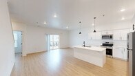 Located at 402 Fast Ln in Hudson, Iowa, this modern 2-bedroom, 3-bathroom multi-floor home is thoughtfully designed across three levels. The ground floor entry features a clean, light-filled foyer with light wood flooring and dark-carpeted stairs with a sleek metal handrail leading to the main living level.

The main floor is anchored by a bright, open-concept kitchen and living room. The kitchen is outfitted with crisp white shaker cabinetry, a large center island with an integrated sink and black fixtures, stainless steel appliances, and stylish pendant lighting. Light wood flooring flows seamlessly into the spacious living area, which opens to a private balcony through sliding glass doors, allowing abundant natural light and neighborhood views.

The upper floor houses both bedrooms and the remaining bathrooms. The generously sized primary bedroom offers a comfortable retreat, while the second bedroom features a large window with natural light and neighborhood views. Closet space is provided in the bedrooms for practical storage. The three bathrooms are finished in a clean, neutral palette with light wood-look flooring, including a walk-in shower unit and a separate bathroom with a soaking tub and natural light from a window. Throughout the home, white walls, recessed lighting, and consistent flooring create a cohesive, modern aesthetic.