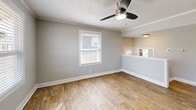 Located at 1 Nevada Avenue in Tacoma, WA, this single-floor, one-bedroom, one-bathroom home offers an efficient and well-organized layout. The living room is a bright, open space featuring warm hardwood-style flooring, a ceiling fan with integrated lighting, crown molding, a textured ceiling, and a window that fills the room with natural light. Adjacent to the living area, the kitchen is equipped with white cabinetry, a gray countertop, a double-basin sink, a white electric range, and a subway tile backsplash, complemented by a large window overlooking the exterior. The bedroom is carpeted and features soft neutral-toned walls, a textured ceiling, and windows that allow ample natural light and neighborhood views. A dedicated closet provides practical storage. The bathroom is cleanly finished with a white vanity, a framed mirror with black hardware, a tub-shower combination with built-in shelving, and a window for natural ventilation. Two utility rooms round out the floor plan, providing additional functional space. Consistent neutral gray wall tones and clean white trim throughout lend the home a cohesive, move-in-ready aesthetic.