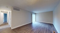 Located at 2400 Shore Blvd W. in Columbus, Ohio, this single-floor unit offers a clean, functional layout with a neutral color palette throughout. The living area is finished with durable wood-look flooring and features a sliding glass door dressed with vertical blinds, allowing natural light to fill the space. A large overhead HVAC vent and textured ceiling are consistent throughout the main living areas, adding to the practical design of the unit. The open layout connects the living space to an entry area, where a white panel front door and glimpse of a refrigerator suggest a combined entry and kitchen zone. The bedrooms are carpeted in a soft, neutral tone and each includes a window with blinds, providing natural light and a comfortable, quiet atmosphere. The bathroom area features wood-look flooring, a marble-patterned countertop with an undermount sink, a well-lit vanity mirror, and a built-in closet with wire shelving for added storage. A separate water closet with a toilet provides additional privacy. Clean white trim, baseboards, and doors are consistent throughout, giving the unit a cohesive, well-maintained appearance that is move-in ready.