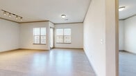 This 2-bedroom, 2-bathroom residence features a clean, modern aesthetic with light-toned wood-style flooring, crisp white walls, and elegant crown molding that runs throughout the single-floor layout. The open-concept kitchen and living area serves as the heart of the home, anchored by a large central island with a dark granite countertop, white cabinetry, a subway tile backsplash, stainless steel appliances, and pendant lighting that adds a contemporary touch. The living area benefits from multiple windows with blinds, allowing generous natural light to fill the space. The primary bedroom is generously sized, featuring a window for natural light and direct access to a spacious walk-in closet with dual hanging rods and shelving on both sides, offering exceptional storage capacity. The second bedroom also includes its own closet and a sliding glass door providing outdoor access. Both bathrooms are finished with modern white cabinetry, dark countertops, and large-format marble-style tile in the tub/shower surrounds. Track lighting appears in select rooms, complementing the overall bright and airy atmosphere. The consistent flooring, neutral color palette, and thoughtful layout create a cohesive and functional living environment throughout.