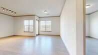 This 2-bedroom, 2-bathroom residence features a clean, modern aesthetic with light-toned wood-style flooring, crisp white walls, and elegant crown molding that runs throughout the single-floor layout. The open-concept kitchen and living area serves as the heart of the home, anchored by a large central island with a dark granite countertop, white cabinetry, a subway tile backsplash, stainless steel appliances, and pendant lighting that adds a contemporary touch. The living area benefits from multiple windows with blinds, allowing generous natural light to fill the space. The primary bedroom is generously sized, featuring a window for natural light and direct access to a spacious walk-in closet with dual hanging rods and shelving on both sides, offering exceptional storage capacity. The second bedroom also includes its own closet and a sliding glass door providing outdoor access. Both bathrooms are finished with modern white cabinetry, dark countertops, and large-format marble-style tile in the tub/shower surrounds. Track lighting appears in select rooms, complementing the overall bright and airy atmosphere. The consistent flooring, neutral color palette, and thoughtful layout create a cohesive and functional living environment throughout.