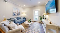 Located in Pensacola, FL, this well-appointed 2-bedroom, 2-bathroom single-story home offers a thoughtfully designed layout that balances comfort and style. The open-concept kitchen and living area serves as the heart of the home, featuring a striking navy blue shiplap island topped with quartz countertops, crisp white shaker cabinets with matte black hardware, stainless steel appliances, and recessed lighting. The adjacent living room is bright and welcoming, with crown molding, hardwood-style flooring, and a glass-paned door that invites natural light. The primary bedroom is a serene retreat, offering generous proportions, natural light through shuttered windows with floral drape accents, and warm hardwood-style floors. The second bedroom includes a dedicated closet and shares a similarly calming aesthetic with soft gray walls and natural light. Both bathrooms are well-finished; one features large-format tile surround in the shower, while the other showcases gray shaker cabinetry, quartz countertops, matte black fixtures, and an arched mirror accent. A dedicated closet adds practical storage. Consistent hardwood-style flooring, neutral tones, and coastal-inspired touches create a cohesive and inviting atmosphere throughout the entire home.