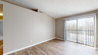 Located at 1050 Cooks Crossing Dr in Milford, Ohio, this single-floor unit offers a practical and well-appointed layout spread across several distinct living areas. The main living space is bright and open, featuring wood-style plank flooring and neutral warm-toned walls that create a clean, inviting atmosphere. A large sliding glass door fitted with vertical blinds allows abundant natural light to fill the room while providing a direct view of the surrounding outdoor scenery.

Adjacent to the living area, the kitchen is efficiently designed with light wood cabinetry extending to the ceiling for ample storage, a white subway tile backsplash, granite countertops, and a stainless steel sink and dishwasher. Black appliances, including a refrigerator and range, complete the functional setup.

A hallway connects the living space to the bedroom, which features soft carpeting and neutral walls, offering a quiet and comfortable retreat. The bathroom is well-finished, showcasing a granite-topped vanity with a framed mirror, white tile surround tub and shower combination, and wood-style flooring that ties cohesively to the rest of the unit. The textured ceilings are consistent throughout, adding subtle character to the overall design.