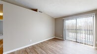 Located at 1050 Cooks Crossing Dr in Milford, Ohio, this single-floor unit offers a practical and well-appointed layout spread across several distinct living areas. The main living space is bright and open, featuring wood-style plank flooring and neutral warm-toned walls that create a clean, inviting atmosphere. A large sliding glass door fitted with vertical blinds allows abundant natural light to fill the room while providing a direct view of the surrounding outdoor scenery.

Adjacent to the living area, the kitchen is efficiently designed with light wood cabinetry extending to the ceiling for ample storage, a white subway tile backsplash, granite countertops, and a stainless steel sink and dishwasher. Black appliances, including a refrigerator and range, complete the functional setup.

A hallway connects the living space to the bedroom, which features soft carpeting and neutral walls, offering a quiet and comfortable retreat. The bathroom is well-finished, showcasing a granite-topped vanity with a framed mirror, white tile surround tub and shower combination, and wood-style flooring that ties cohesively to the rest of the unit. The textured ceilings are consistent throughout, adding subtle character to the overall design.