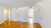 Located at 1-186 Nottingham Ct, this one-bedroom, one-bathroom residence offers a thoughtfully arranged single-floor layout that makes efficient use of its space. Warm-toned hardwood floors flow throughout the living areas, hallway, and bedroom, lending a cohesive and inviting feel to the interior. The living room features notable vaulted ceilings that enhance the sense of openness, with a front entry door featuring small transom windows that allow natural light to filter in. The spacious bedroom is well-proportioned, includes a large sliding double-door closet, and benefits from a bright window overlooking the exterior. The kitchen is equipped with warm wood cabinetry, a gas range, a sink with countertop workspace, and a window for natural ventilation, along with light tile flooring that contrasts with the hardwood found elsewhere. The full bathroom includes a tiled tub-and-shower surround, a vanity with cabinet storage, tile flooring, and a window for natural light. A connecting hallway ties the rooms together efficiently. Throughout the unit, crisp white walls and ample natural light create a clean, neutral backdrop well-suited for a variety of living arrangements.