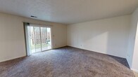 Located at 5144 S Webster St, Apt A in Kokomo, Indiana, this single-floor apartment offers a straightforward and functional layout across several well-defined living spaces. The interior features neutral cream-colored walls throughout, complemented by textured ceilings that add subtle character to each room.

The spacious living room is carpeted and bathed in natural light through a large sliding glass door that opens to a private, fenced outdoor area, providing both a sense of openness and outdoor access. The dining area transitions seamlessly from the living space, featuring tile flooring and a pass-through opening that connects to the kitchen, enhancing the flow between rooms.

The kitchen is equipped with warm wood-toned cabinetry, granite-style countertops, tile flooring, and white appliances including a refrigerator and range, offering practical functionality in a compact, efficient space.

The bedrooms are carpeted and well-lit, with one bedroom featuring a window with views to the exterior and convenient proximity to the full bathroom. The bathroom includes a tub and shower combination with a curtain surround, presented in clean, neutral tones.

Overall, this apartment presents a clean, move-in ready environment with consistent finishes and a practical single-level layout suited for comfortable everyday living.