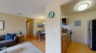 Located at 2540 Sunset Dr in Longmont, Colorado, this single-floor residence offers a well-designed layout that balances comfort and functionality. The open-concept living and dining area is anchored by warm neutral tones, plush carpet, and hardwood-style flooring that flows seamlessly between spaces. The living room is a standout, featuring a tile-surround fireplace, an eye-catching wall sculpture, and a sliding glass door that opens to a private balcony overlooking the surrounding neighborhood. Natural light fills the room, enhancing the inviting ambiance. Adjacent to the dining area, the kitchen is accessible via a pass-through bar with granite-style countertops, and is equipped with stainless steel appliances, a range, microwave, and ample cabinetry with a built-in range hood. The dining space comfortably accommodates a full table set beneath a pendant light. Two well-proportioned bedrooms each feature plush carpet, generous natural light from sizable windows, and soft neutral walls. The bathrooms include a vanity with wood-tone cabinetry and a full tub-shower combination with classic white tile accenting. Throughout the residence, textured ceilings and consistent warm tones create a cohesive and comfortable living environment.