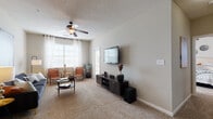 This single-story model home located on Shiloh Valley Dr NW in Kennesaw, Georgia, presents a well-organized layout designed for comfortable everyday living. The interior is characterized by a consistent neutral color palette of warm grays and soft whites, creating a cohesive and inviting atmosphere throughout.

The living room is a generously sized space featuring plush wall-to-wall carpeting, a ceiling fan with integrated lighting, and multiple windows dressed with sheer white curtains that allow ample natural light to fill the room. The dining area is accessed through an open archway and is illuminated by a pendant light fixture, complementing the carpeted floor that continues from the living space.

The kitchen is outfitted with white cabinetry, granite-style countertops, a decorative tile backsplash, and stainless steel appliances, including a range, over-the-range microwave, and dishwasher. Wood-look flooring grounds this functional space.

The bedrooms offer comfortable retreats, each with carpeted floors, neutral walls, and windows providing natural light. The bathroom features wood-look flooring, a white vanity with granite-style countertops, a large mirror, and a multi-bulb vanity light fixture. The overall design of this model home reflects a clean, modern aesthetic suitable for a variety of lifestyles.