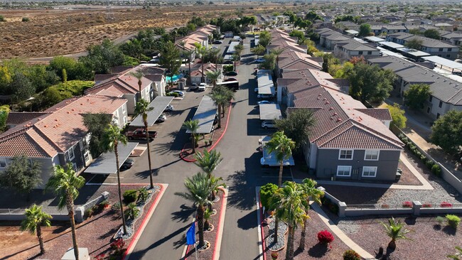 Experience desert living at its finest! This aerial view of Sedona Peaks highlights the beautiful community layout, complete with lush palm trees and breathtaking mountain views. - Sedona Peaks