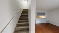 Located in Austin, TX, this two-bedroom, one-bathroom two-story home offers a functional and well-organized layout spread across two floors. The ground floor hosts the living room and kitchen, while the upper floor accommodates both bedrooms, a hallway, a closet, and the shared bathroom.

The kitchen is equipped with stainless steel appliances, including a range and refrigerator, complemented by gray shaker-style cabinetry, white countertops, and a window that brings in natural light. Wood-look flooring runs throughout the main level, adding warmth to the space.

A carpeted staircase with a handrail connects the two floors. Upstairs, both bedrooms feature wood-look flooring and white walls. The primary bedroom includes a ceiling fan, while the second bedroom benefits from a window with blinds that allows natural light. A sliding door with vertical blinds is also present in one of the upper-level rooms. The shared bathroom is outfitted with a tub/shower combination featuring clean white tile surround.

Throughout the home, textured ceilings, neutral white walls, and consistent flooring create a cohesive, clean aesthetic. The layout is efficient, making practical use of the available space across both levels.