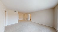 This single-floor residence is designed with a clean, neutral aesthetic that emphasizes functionality and comfort throughout. The main living area is generously proportioned, featuring plush wall-to-wall carpeting, neutral beige walls, and a built-in shelving unit with cabinet storage below — a practical and decorative focal point. The space flows openly toward the kitchen and bedroom areas, lending an airy, connected feel.

The galley-style kitchen is well-equipped with white cabinetry, a double stainless steel sink, light stone countertops, hardwood-style flooring, and a white range with overhead ventilation. A pendant light fixture adds a warm touch, and a pass-through view connects the kitchen to the adjacent living space.

The bedrooms are carpeted and bright, each featuring ceiling fan light fixtures. The primary bedroom includes direct access to a full bathroom and a large walk-in closet outfitted with dual hanging rods and shelving. A second walk-in closet provides additional storage. Both bathrooms include tub-shower combinations with tile surrounds and hardwood-style flooring.

Overall, the space maintains a light, cohesive palette of whites and warm neutrals, creating a clean and welcoming environment throughout.