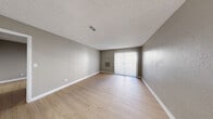 Located at 2255 E Sunset Rd in Las Vegas, Nevada, this single-floor unit offers a clean, modern aesthetic throughout its well-appointed layout. Consistent light wood-look flooring runs through every room, complemented by neutral gray walls, crisp white baseboards, and textured ceilings that together create a cohesive and contemporary feel.

The living area is open and spacious, featuring a sliding glass door with vertical blinds that allows natural light to fill the room while providing access to an outdoor area. A wall-mounted HVAC unit ensures year-round comfort. Adjacent to the living space is a dedicated dining area with a window fitted with horizontal blinds, and a stainless steel refrigerator nearby signals the transition to the kitchen.

The kitchen is well-equipped with gray shaker-style cabinetry, a stainless steel refrigerator, electric range, and over-the-range microwave, offering ample functionality for everyday cooking. The bedrooms are generously sized, each featuring ceiling fans with light fixtures and windows with blinds that bring in natural light.

The bathroom is tastefully updated, showcasing a white vanity with a granite-style countertop, a backlit LED mirror, brushed nickel fixtures, and a shower-tub combo. Every detail of this unit reflects a thoughtfully refreshed interior designed for comfortable, functional living in Las Vegas.