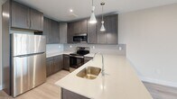 Located at 70 Church St in Flemington, NJ, this modern two-story unit offers a thoughtfully designed layout spread across two floors. The main level features an open-concept kitchen and living area bathed in natural light, with direct access to a private balcony offering pleasant outdoor views. The kitchen is a standout, showcasing rich dark cabinetry, light quartz countertops, a large peninsula with an undermount sink, stylish pendant lighting, and stainless steel appliances — including a refrigerator, range, and microwave. Light wood-tone flooring flows throughout, complementing the clean, contemporary aesthetic. A convenient in-unit laundry area and multiple closets provide ample storage on this level. Two full bathrooms serve the unit, each finished with crisp white fixtures, dark tile flooring, and matte black hardware accents, with one featuring a soaking tub and tiled surround. The upper floor is home to the generously sized primary bedroom, which is bright and airy, featuring recessed lighting, a wall-mounted mini-split system, soft neutral tones, and large windows that frame open views of the surrounding area. The overall ambiance is fresh, clean, and move-in ready.