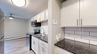 Located at 7945 Mentor Ave in Mentor, OH, this 2-bedroom, 1-bathroom unit offers a well-organized single-floor layout designed for comfortable everyday living. The open living room features light wood-style flooring, neutral wall tones, a ceiling fan, and a sliding glass door that fills the space with natural light and provides outdoor views. The galley-style kitchen is thoughtfully updated with white shaker cabinets, dark granite countertops, a classic subway tile backsplash, and a full suite of stainless steel appliances including a range, microwave, and refrigerator. Both bedrooms are carpeted and finished in soft neutral tones. The primary bedroom is generously sized, offering two windows for natural light, a ceiling fan, and baseboard heating. The second bedroom features a large sliding-door closet, providing ample storage. A connecting hallway links the bedrooms to the full bathroom, which is clean and bright with a white vanity, tub-shower combo, built-in shower shelving, and a frosted window for privacy. The overall aesthetic is fresh and move-in ready, with consistent neutral finishes and updated flooring throughout the main living areas.