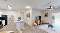 Located at 6001 Thomaston Rd in Macon, GA, this single-story 2-bedroom, 2-bathroom home offers a well-designed open-concept layout that connects the kitchen, dining, and living areas into one cohesive, functional space. The kitchen is a standout feature, showcasing crisp white shaker cabinetry with black hardware, a tiled backsplash, black appliances, and a central island with a built-in sink and generous counter space. A dedicated pantry with louvered doors provides excellent storage. Light wood-style flooring flows throughout, lending warmth and continuity across every room. The dining area offers a bright, airy setting, while the living room is comfortable and well-proportioned. The spacious primary bedroom features a ceiling fan, natural light from a large window with blinds, and a walk-in closet with wire shelving. The second bedroom is equally well-appointed. Both bathrooms are finished in a clean, contemporary style with white vanities, black fixtures, large mirrors, and tub-shower combinations. A hallway connects the private areas of the home, and two closets offer additional storage. The overall aesthetic is modern and neutral, with consistent finishes throughout that create a cohesive and inviting atmosphere.