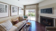 This single-floor residence offers a thoughtfully designed layout with a cohesive blend of warm finishes and modern fixtures throughout. The open-concept kitchen is a standout feature, equipped with stainless steel appliances, rich cherry wood cabinetry extending to the ceiling, granite countertops, and a central island with a double sink and pendant lighting above. Dark hardwood flooring runs through the main living areas, adding warmth and continuity. A built-in desk nook within the kitchen provides a functional workspace. The dining area flows naturally from the kitchen, creating an ideal setting for entertaining.

The living room features rich hardwood floors, a tiled fireplace, and sliding glass doors that open to a private outdoor patio, allowing ample natural light. Horizontal striped wall treatments add a distinctive design element throughout the common areas.

Both bedrooms are carpeted and bright, with windows offering natural light. The primary bathroom includes a double-sink granite vanity, dark wood cabinetry, large-format tile flooring, a soaking tub, and access to a walk-in closet. A secondary bathroom mirrors the refined aesthetic with a tub-shower combination and granite countertops.