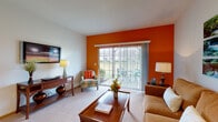Located at 4333 Parkway Village Dr in Grove City, Ohio, this single-floor residence offers a thoughtfully designed layout that balances comfort and functionality. The living room serves as the heart of the home, highlighted by a bold burnt-orange accent wall that adds warmth and character. A large sliding glass door floods the space with natural light and opens to an outdoor patio with pleasant green views, while plush carpeting and ample room for seating create a welcoming atmosphere. An adjacent seating nook provides additional lounging space, making the living area versatile and inviting. The kitchen is well-equipped with warm oak cabinetry, stainless steel appliances including a range, microwave, refrigerator, and dishwasher, all set atop durable hardwood-style flooring. A breakfast bar adds casual dining convenience. The two bedrooms are comfortably proportioned, each featuring plush carpet, generous closet space, and large windows that invite natural light. The primary bedroom offers outdoor views through sheer-curtained windows. The bathroom is clean and functional, featuring a wooden vanity with ample storage, a large mirror, and hardwood-style flooring. Overall, the space presents a cohesive, comfortable living environment with practical finishes throughout.