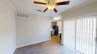 Located in Georgetown, TX, this single-floor, two-bedroom, one-bathroom unit offers an efficient and practical layout. The living area greets you with wood-look hardwood-style flooring, neutral gray walls, crown molding, and a ceiling fan with a light fixture, creating a clean and airy atmosphere. Vertical blinds along one wall provide privacy and light control. The open-concept flow leads directly into the kitchen, which features dark espresso-toned cabinetry reaching to the ceiling for generous storage, white countertops, a stainless steel double-basin sink, and black appliances including a range and over-the-range microwave. The primary bedroom is a comfortable size, complete with plush carpeting, a ceiling fan, mirrored sliding closet doors, and a window that invites natural light. The second bedroom also features soft carpeting, neutral walls, and a ceiling fan. The shared bathroom includes a full tub-shower combination with white tile surround and dark wood cabinetry overhead for additional storage. Throughout the unit, textured ceilings and consistent neutral tones create a cohesive and functional living environment well-suited for everyday comfort.