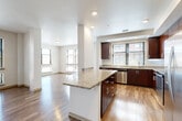 Located at 3458 S Gaylord Ct in Englewood, Colorado, this single-floor, 2-bedroom, 2-bathroom residence offers a thoughtfully designed layout with modern finishes throughout. The open-concept kitchen and living area serves as the heart of the home, featuring rich dark-wood cabinetry, granite countertops, a central island, and a full suite of stainless steel appliances. Hardwood-style flooring runs throughout the main living spaces, reflecting natural light that pours in through a generous bank of large windows. The living room is bright and spacious, offering a clean, airy ambiance well-suited for both relaxing and entertaining. Two hallways connect the living spaces to the private quarters, providing a functional and well-organized flow. The generously sized primary bedroom is carpeted for comfort and includes two separate doorways leading to additional spaces such as a closet or en-suite bath. The second bedroom is equally well-lit, with a wide window overlooking the exterior. Both bathrooms are finished with tile flooring, granite-topped dark wood vanities, and full tub and shower combinations. A dedicated laundry room with a front-loading washer and dryer adds everyday convenience. The overall aesthetic is clean, contemporary, and move-in ready.