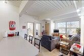 Located at 18 N Randall Ave in Madison, WI, this single-floor unit offers three bedrooms and two bathrooms within a efficiently laid-out floor plan. A standout architectural feature is the distinctive slatted white ceiling that runs through the living area and kitchen, adding visual character to the space.

The living room is bright and inviting, benefiting from large windows that bring in generous natural light and outdoor views of the surrounding neighborhood. Carpet flooring adds warmth underfoot throughout the living and sleeping areas. The open sightlines from the kitchen counter into the living room create a connected, social atmosphere.

The kitchen is well-equipped with light wood cabinetry — both upper and lower — open shelving, a full-size refrigerator, dishwasher, and a stove, offering solid functionality within a compact footprint. Light wood-style flooring runs through the kitchen and entry area.

The bedrooms each feature carpet flooring, ample natural light from windows, and closet storage. The primary bedroom is comfortably sized with room for a bed, desk, and dresser. The two bathrooms include light wood-tone flooring and tub-shower combinations. A central hallway connects the bedrooms and bathrooms, keeping the layout organized and accessible. The front entry area provides convenient coat storage space near the door.