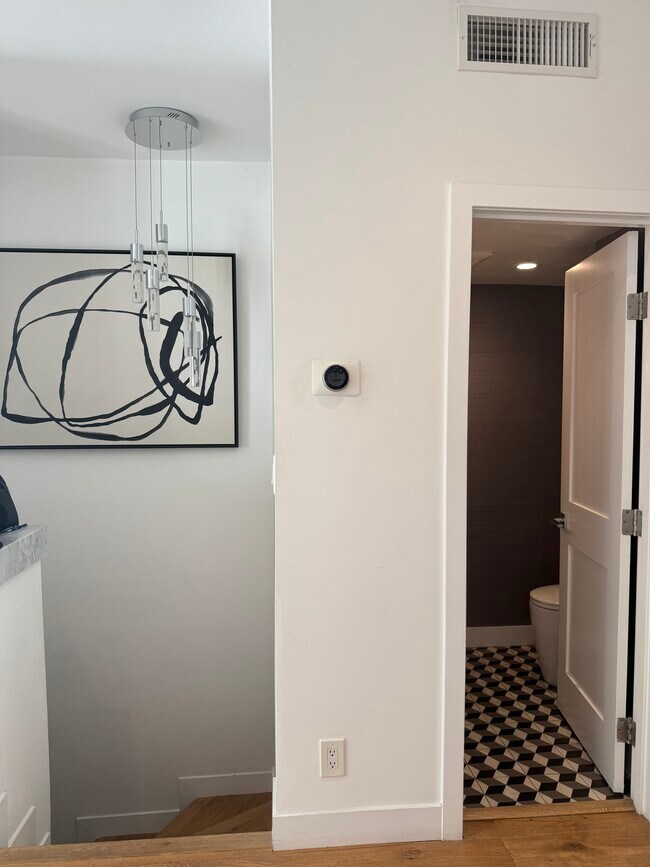 Escaleras que bajan a la sala adicional y al garaje privado. - 8611 Burton Way