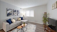 This single-floor unit offers a thoughtfully designed layout across several well-defined living spaces. The living room serves as the heart of the home, featuring durable wood-style flooring, a textured ceiling, and a window fitted with blinds that allows natural light to fill the room. Neutral gray walls provide a versatile backdrop throughout.

The kitchen is efficiently designed with ample white cabinetry accented by warm wood trim, marble-style countertops, and stainless steel appliances including a refrigerator, dishwasher, and electric range. A ceiling fan with light fixture overhead and wood-style flooring complete the space, which connects seamlessly to a dining area with room for a small table.

The primary bedroom features plush carpet flooring, a window with blinds for natural light, and a textured ceiling, offering a comfortable and quiet retreat. A secondary room with carpet flooring and a window provides flexible use as an additional bedroom or home office.

The bathroom includes a full tub and shower combo, wood-style flooring, and clean, functional fixtures. Throughout the unit, consistent gray-toned walls and neutral finishes create a cohesive, modern aesthetic that is both practical and inviting.