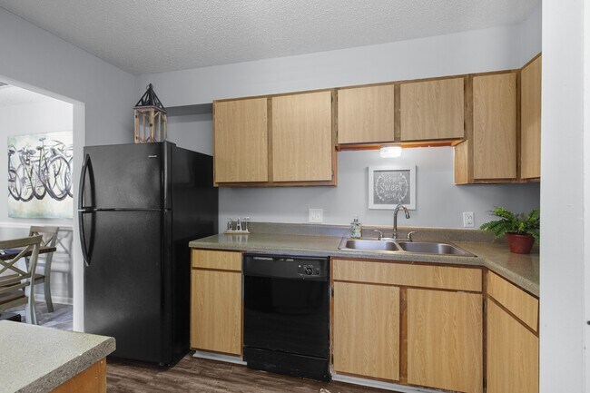 Electrodomésticos elegantes y a juego en color negro, combinados con cálidos gabinetes de madera, se unen en las cocinas de los apartamentos Lakeland East en Flowood, Mississippi. Administrados por Highlands Vista Group. - Lakeland East