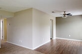 This single-story home offers a well-organized, functional layout designed for comfortable everyday living. The living area is spacious and carpeted, bathed in natural light streaming through a large sliding glass door fitted with vertical blinds that opens to a lush green outdoor view. Adjacent to the living area, the flooring transitions to wood-look planks, leading into a dining or secondary living space equipped with a ceiling fan and light fixture overhead.

The kitchen is thoughtfully designed with white cabinetry, a white subway tile backsplash, light-toned countertops, and a full suite of stainless steel appliances including a refrigerator, dishwasher, and range. Wood-look flooring continues throughout this area, adding warmth and cohesion.

The home includes multiple bedrooms, each carpeted and finished with neutral-toned walls. The primary bedroom features dual windows that allow for generous natural light, complemented by a ceiling fan. Additional bedrooms offer ample space and individual windows.

Two bathrooms serve the home: one features a full tub-shower combination with white tile surround, while the second includes a standalone shower, wood-look flooring, and a dark-toned vanity. Textured ceilings are consistent throughout, and clean white baseboards frame each room, completing the home's tidy, move-in-ready appearance.