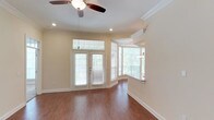 This single-floor residence offers a thoughtfully designed layout that balances comfort and functionality throughout. A hardwood-floored entryway leads into an expansive open living area, where warm hardwood-style flooring, crown molding, recessed lighting, and a ceiling fan create an inviting atmosphere. French doors topped with a transom window flood the space with natural light and provide access to the outdoors, while a curved bay window adds architectural character to a dedicated dining nook. The open-concept kitchen is a standout feature, equipped with stainless steel appliances including a range, microwave, and refrigerator, complemented by white shaker cabinetry, granite countertops, a tile backsplash, and a convenient breakfast bar that connects to the living area. The two bedrooms are carpeted and feature ceiling fans, offering a quiet and comfortable retreat, each with ample natural light from large windows. The primary bathroom is well-appointed with a dual-sink granite vanity, a soaking tub, and a separate glass-enclosed walk-in shower with white tile surround. A second full bathroom features a granite vanity and a combination tub and shower. An in-unit washer and dryer are also present, adding everyday convenience to this polished and move-in-ready home.