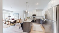 Located at 14504 Abbeyfield Ave in Rosemount, MN, this single-floor, 2-bedroom, 2-bathroom home offers a thoughtfully designed layout with contemporary finishes throughout. The open-concept kitchen is a standout feature, showcasing two-tone cabinetry — crisp white uppers paired with dark lower cabinets — complemented by granite countertops, a central island with bar seating, stainless steel appliances, and light hardwood-style flooring. Pendant lighting above the island adds a stylish touch, while the kitchen flows seamlessly into the living room, which is filled with natural light from large sliding glass doors fitted with vertical blinds. The primary bedroom is a comfortable retreat featuring plush carpet, a sliding glass door that invites natural light and outdoor views, and ample closet space. The second bedroom is equally well-sized with its own closet access. Both bathrooms are finished with granite countertops, white cabinetry, and neutral tile flooring, with the full bath offering a tub-shower combination. A dedicated laundry area includes a stacked washer and dryer unit alongside additional storage shelving, adding practical convenience to this well-rounded home.