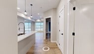 This thoughtfully designed one-bedroom, one-bathroom unit at 8455 106A Ave NW offers a modern aesthetic supported by quality finishes throughout. Warm hardwood-style flooring runs continuously across the entire space, creating a cohesive and inviting atmosphere.

The open-concept kitchen and living area forms the heart of the unit. The kitchen is outfitted with two-tone cabinetry in soft blue-grey and white, a clean white quartz countertop with an undermount stainless steel sink, stainless steel appliances including a refrigerator, range, and microwave, and geometric pendant lighting that adds a contemporary touch. A decorative textured accent wall in the living area serves as a standout architectural detail.

Large windows in the living area flood the space with natural light and provide open exterior views. The bedroom is a well-proportioned room featuring a large window with a roller blind, neutral warm-toned walls, and continued hardwood-style flooring.

The bathroom is finished with large-format light grey wall tiles surrounding a soaking tub, complemented by built-in open shelving and white cabinetry for storage. A dedicated closet provides additional practical storage. The unit's neutral palette and modern detailing create a clean, functional living environment.