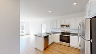 Located at 268 Market St in South Burlington, Vermont, this modern 3-bedroom, 3-bathroom unit offers a thoughtfully designed single-floor layout. Light-toned hardwood flooring runs throughout, creating a cohesive and bright aesthetic across all rooms.

The open-concept kitchen and living area serves as the heart of the unit. The kitchen is well-appointed with white shaker cabinetry, dark speckled countertops, a peninsula with a double stainless steel sink, and a full suite of stainless steel appliances including a range, over-the-range microwave, dishwasher, and refrigerator. Recessed lighting illuminates the space efficiently.

Each of the three bedrooms features crisp white walls and generous natural light. The spacious primary bedroom includes a wall-mounted mini-split air conditioning unit and large windows offering views of the surrounding South Burlington streetscape. Secondary bedrooms are equally bright, with one featuring a double-door closet. Baseboard heating is present throughout.

The three bathrooms are clean and functional, finished in white with wood-look flooring. Bathrooms include tub/shower combinations with curved curtain rods and brushed nickel fixtures, as well as white vanities with ample storage.

The unit's overall design is modern and minimalist, with an abundance of natural light, a neutral palette, and practical finishes suited for comfortable everyday living.