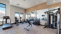 Located in Colorado Springs, CO, this modern fitness center offers a comprehensive exercise space designed to support a wide range of workout routines. The room features a clean, contemporary aesthetic with crisp white walls accented by warm tan upper panels, recessed lighting, and neutral-toned carpet flooring throughout.

Large windows line multiple walls, flooding the space with abundant natural light and providing views of the surrounding outdoor area, including glimpses of a pool and the Colorado landscape. A full-length mirror along one wall visually expands the room and enhances the open, airy feel.

The facility is outfitted with an impressive array of equipment, including multiple treadmills, upright and recumbent stationary bikes, a rowing machine, and a cable/multi-functional strength machine. A dumbbell rack stocked with a full range of free weights and an adjustable weight bench provide options for strength training. Medicine balls and resistance accessories are also available for functional fitness workouts, and a mounted flat-screen display offers additional utility.

Glass-panel doors connect to an adjacent room, contributing to the open, community-oriented layout. The overall ambiance is bright, clean, and functional, making this fitness center a well-appointed space for residents seeking convenient, on-site exercise facilities.