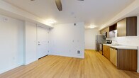 Located at 10423 E Burnside St in Portland, Oregon, this efficiently designed single-floor unit offers a thoughtful layout that maximizes every square foot. The open-plan kitchen and living area serves as the heart of the space, featuring light hardwood-style flooring that runs throughout, crisp white walls, and a ceiling fan with integrated lighting that enhances air circulation and ambiance. A large window allows natural light to fill the living area, creating a bright and welcoming atmosphere.

The kitchen is well-appointed with warm wood-toned cabinetry, white quartz-style countertops, a stainless steel refrigerator, gas range, and built-in microwave. The galley-style layout provides an efficient workflow while maintaining a clean, contemporary aesthetic. A louvered closet door in the kitchen corridor offers additional storage access.

The bathroom features a wood-grain vanity with a white countertop, an undermount sink, brushed nickel hardware, and a large mirror with overhead lighting, lending a clean and modern feel. A walk-in closet provides practical storage off the living area. The unit's neutral palette, consistent flooring, and modern finishes create a cohesive and functional living environment suited for everyday comfort in the heart of Portland.