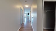 Located at 2760 S Highland Ave in Lombard, IL, this single-floor unit offers a thoughtfully designed, modern layout. A clean, well-lit hallway with hardwood-style flooring and neutral gray walls provides a welcoming entry, connecting the various rooms seamlessly.

The open-concept kitchen and living area serves as the heart of the unit. The kitchen is outfitted with dark espresso cabinetry, stainless steel Whirlpool appliances including a gas range, over-the-range microwave, and refrigerator, complemented by granite countertops and a tile backsplash with under-cabinet accent lighting. A peninsula with pendant lighting doubles as a breakfast bar and separates the kitchen from the spacious living area, which features hardwood-style flooring and large windows that flood the space with natural light. Sliding glass doors lead to a private balcony, offering pleasant outdoor views.

The unit includes two bedrooms, each carpeted for comfort and equipped with windows providing natural light. The bathrooms are finished with light wood-look tile flooring. One bathroom features a walk-in glass-enclosed shower with white tile surround, while the second includes a vanity with dark cabinetry and a grab bar for accessibility. Throughout, the unit maintains a clean, contemporary aesthetic with neutral tones and quality finishes.