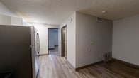 Located at 2510 Washington Blvd in Ogden, Utah, this single-floor unit offers a practical and updated living space with a clean, modern aesthetic throughout. The interior features a mix of durable wood-look vinyl plank flooring in the main living and kitchen areas, complemented by bold geometric-patterned carpeting in the bedroom spaces, adding a distinctive visual element to the layout.

The kitchen is equipped with a stainless steel refrigerator and connects seamlessly to a hallway that leads to the various rooms, creating an efficient flow throughout the unit. The hallway features track lighting and neutral gray walls, contributing to a bright and open feel.

The living areas are finished with neutral gray walls, dark baseboards, and textured ceilings, providing a contemporary and cohesive design palette. Bedroom spaces offer built-in closets with shelving and natural light from windows fitted with horizontal blinds.

The bathroom is well-appointed, featuring wood-look tile flooring, a soaking bathtub with a curved shower curtain rod, a vanity with a white countertop and cabinetry, and a recessed ceiling light. Grab bars and towel racks add practical functionality to the space. Overall, the unit presents a clean, move-in ready environment with updated finishes throughout.