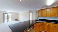Located at 1400 Worcester Rd in Framingham, Massachusetts, this single-floor unit offers a well-organized and functional layout. The kitchen is a standout feature, showcasing rich wood cabinetry, dark granite countertops, and a full suite of stainless steel appliances including a refrigerator, range, microwave, and dishwasher. A curved peninsula provides additional prep space and creates a natural transition into the open living area. Recessed lighting and under-cabinet fixtures ensure the kitchen is well-lit throughout. The living area is generously proportioned, finished with soft wall-to-wall carpeting and neutral, light-toned walls that lend a clean and airy feel. A window in the bedroom area brings in natural light and offers a pleasant outdoor view of surrounding greenery. Baseboard heating and a wall-mounted HVAC unit provide climate control throughout the space. The bathroom features a full soaking tub with white subway tile surround and chrome fixtures, offering a classic, clean aesthetic. Overall, the unit presents a practical and comfortable living environment with a cohesive design marked by warm wood tones, neutral finishes, and well-placed amenities throughout.
