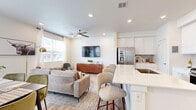 Located at 6205 Longstem Way in Loveland, Colorado, this contemporary two-story home offers a well-organized layout across two floors. The main level features an open-concept living, dining, and kitchen area bathed in natural light from large windows. The kitchen is outfitted with crisp white cabinetry, a subway tile backsplash, stainless steel appliances including a range and microwave, and a sleek white quartz island with an undermount sink and bar seating — ideal for both cooking and casual dining. Light wood-tone flooring flows throughout the main level, complementing the clean, neutral palette. The adjacent dining area accommodates a full dining table and benefits from bright window views, while the living room features recessed lighting and a ceiling fan. The upper floor houses all three bedrooms, including a generously sized primary bedroom with plush carpet, elevated ceilings, a ceiling fan, and a walk-in closet. Additional bedrooms include double-door closets and soft carpeting. Five bathrooms are distributed across both floors for ample convenience. A dedicated laundry room with a full-size washer and dryer adds everyday practicality. The attached garage provides secure parking and additional storage. The home's modern design, neutral finishes, and functional layout make it a comfortable and stylish residence.