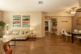 Located at 79090 Avenue 42 in Bermuda Dunes, CA, this single-story residence offers a thoughtfully designed layout with a warm, coastal-inspired aesthetic throughout. The open-concept living and dining area serves as the heart of the home, showcasing wood-look flooring, neutral walls, and vibrant artwork that adds a pop of color. Floating shelves and a built-in desk nook provide functional, modern touches, while sliding glass doors in the living room invite natural light and offer access to an outdoor patio area with lush greenery visible beyond.

The kitchen is well-appointed with warm wood cabinetry, granite-look countertops, stainless steel appliances including a gas range and built-in microwave, and a breakfast bar peninsula. Bedrooms are carpeted for comfort — one features a striking wood-paneled accent wall and ample natural light, while another offers dual windows with views of the surrounding landscape. Both bathrooms are finished with wood-look flooring, warm-toned vanity cabinetry, and tub/shower combinations. The cohesive design elements, including the consistent flooring, neutral palette, and coastal accents, create a bright, inviting atmosphere suited to the sunny Southern California desert setting.