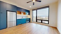 This 470 square foot studio apartment in Washougal, WA, exemplifies efficient modern living. The open-concept design maximizes space utilization, with a seamless flow between living areas. The kitchen stands out with its sleek blue cabinetry, stainless steel appliances, and a window offering scenic views. Wood-look flooring throughout adds warmth and continuity.

The bathroom features a white color scheme with black fixtures, including a bathtub-shower combination and modern toilet. A mosaic tile floor adds texture and interest. The main living area is versatile, with ample natural light and a ceiling fan for comfort. Climate control is ensured by both the ceiling fan and a wall-mounted air conditioning unit.

Storage solutions include a closet and kitchen cabinets. The apartment's single floor layout and hallway provide easy navigation. Despite its compact size, the space feels open and airy, thanks to its thoughtful design and large windows that bring the outside in, creating a connection with the surrounding landscape.