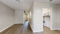 This well-organized single-floor unit offers a practical and comfortable layout designed to maximize every square foot. Warm wood-look flooring runs consistently throughout the space, complemented by neutral-toned walls and white trim that give the interior a clean, cohesive appearance. A textured ceiling adds subtle character to each room.

The galley-style kitchen is efficiently arranged with white cabinetry, a countertop with a built-in sink, and white appliances including a refrigerator, electric range, and microwave. A pass-through opening connects the kitchen to the adjacent dining area, promoting an open and connected feel between the two spaces.

A central hallway links the main living and dining area to the private quarters, creating a clear and logical flow throughout the unit. The bedroom is a well-proportioned room featuring a ceiling fan with light fixture, a window with a view of surrounding greenery, and a sliding-door closet offering shelving and hanging space. An additional dedicated closet provides further storage.

The full bathroom is equipped with a combination tub and shower, a vanity with countertop storage, a toilet, and an over-toilet cabinet for added convenience. Throughout, the unit maintains a bright, neutral aesthetic that is both functional and easy to personalize.