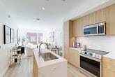 Located at 5300 Wisconsin Ave in Washington, DC's Chevy Chase neighborhood, this thoughtfully designed one-bedroom, one-bathroom residence offers a seamless blend of modern aesthetics and functional living. The open-concept layout unites the kitchen, dining, and living areas into a single cohesive space filled with natural light from large windows that frame views of the surrounding brick streetscape.

The kitchen is a standout feature, showcasing light wood cabinetry extending to the ceiling, a striking marble-look quartz waterfall island with an undermount sink, and a full suite of stainless steel appliances including a slide-in range, built-in microwave, and French door refrigerator. A marble-tiled backsplash adds a refined touch to the clean, contemporary design. Light hardwood flooring flows throughout the main living areas, enhancing the bright and airy atmosphere.

The living area provides a comfortable retreat with ample space for seating and entertaining. The bedroom offers a serene escape, featuring a patterned accent wall, a large window with natural light, and generous closet space. The bathroom is finished with a wood-toned vanity, white subway-tiled tub-shower combination, and clean white fixtures. Additional conveniences include in-unit laundry and a dedicated utility room.