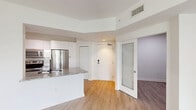 Located at 8150 NW 53rd St in Doral, FL, this well-appointed 2-bedroom, 1-bathroom unit offers a clean, modern aesthetic with a thoughtfully designed layout. Light wood-style flooring runs throughout the entire space, complementing the crisp white walls and creating a bright, cohesive feel.

The open-concept kitchen and living area serves as the heart of the unit. The kitchen features sleek white cabinetry extending to the ceiling for ample storage, a full suite of stainless steel appliances including a French door refrigerator, electric range, and microwave, as well as a granite-topped peninsula with an undermount sink — ideal for casual dining or meal prep. The adjacent living area is generously proportioned and receives abundant natural light through a sliding glass door that opens to a balcony with tropical palm views.

Both bedrooms are comfortably sized, each featuring windows with horizontal blinds that allow for natural light and privacy. The primary bedroom includes access to a dedicated closet.

The bathroom is finished with a granite-top vanity, a large framed mirror, black matte fixtures, and a tiled shower-tub combination. A hallway connects the main living areas to the private quarters, completing this efficient and modern floor plan.